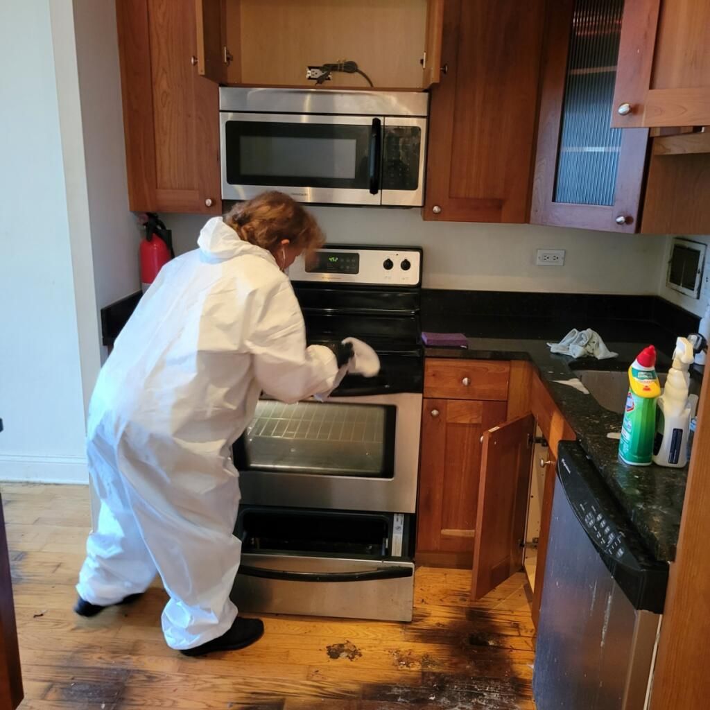 Team member deep-cleaning an oven in full protective gear
